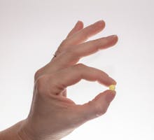 Hand holding up a single baby aspirin