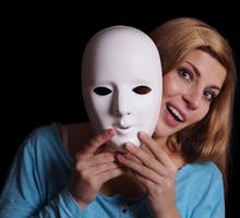 smiling young woman removing plain white mask from her face