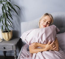 Woman hugs a pillow in bed. Do you love your pillow this much?