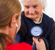 Young doctor measures the elderly woman blood pressure