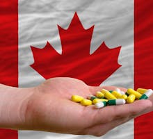 man holding pills in front of a Canadian Flag