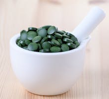 green chlorophyll pills in a ceramic mortar and pestle