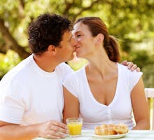 a couple kissing over breakfast