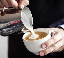 Closeup of barista making coffee and pouring milk
