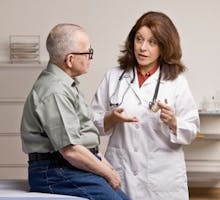 A female doctor talking with an older male patient,