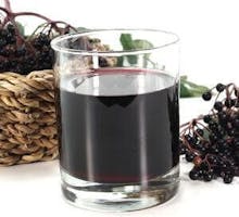 a glass of elderberry juice and elderberries