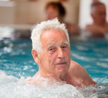 Elderly man enjoying in pool with hot water in spa resort