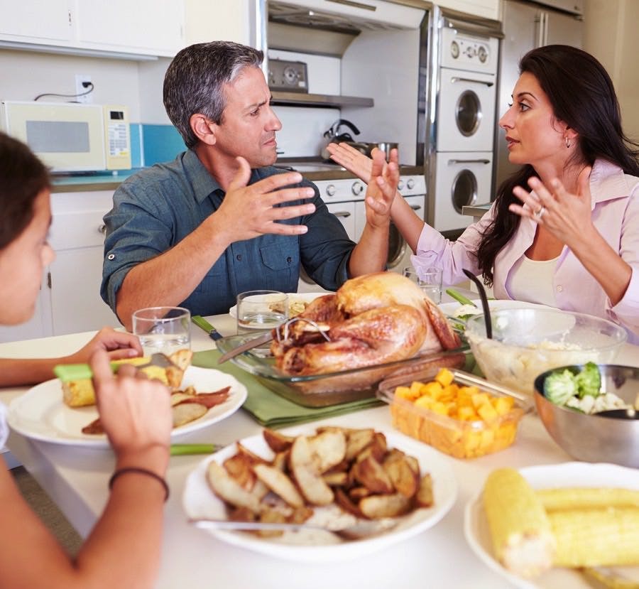 Family Having Argument Sitting Around Table Eating Meal
