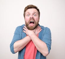 Frightened bearded man clutches his throat because of angioedema