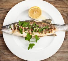 a plate with grilled sea bass and a lemon