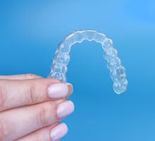 Hand holds transparent orthodontic fixture