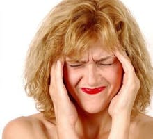 woman with a migraine headache massages her temples