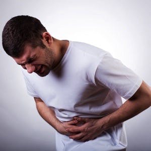 Young man with severe stomach ache holding his stomach

