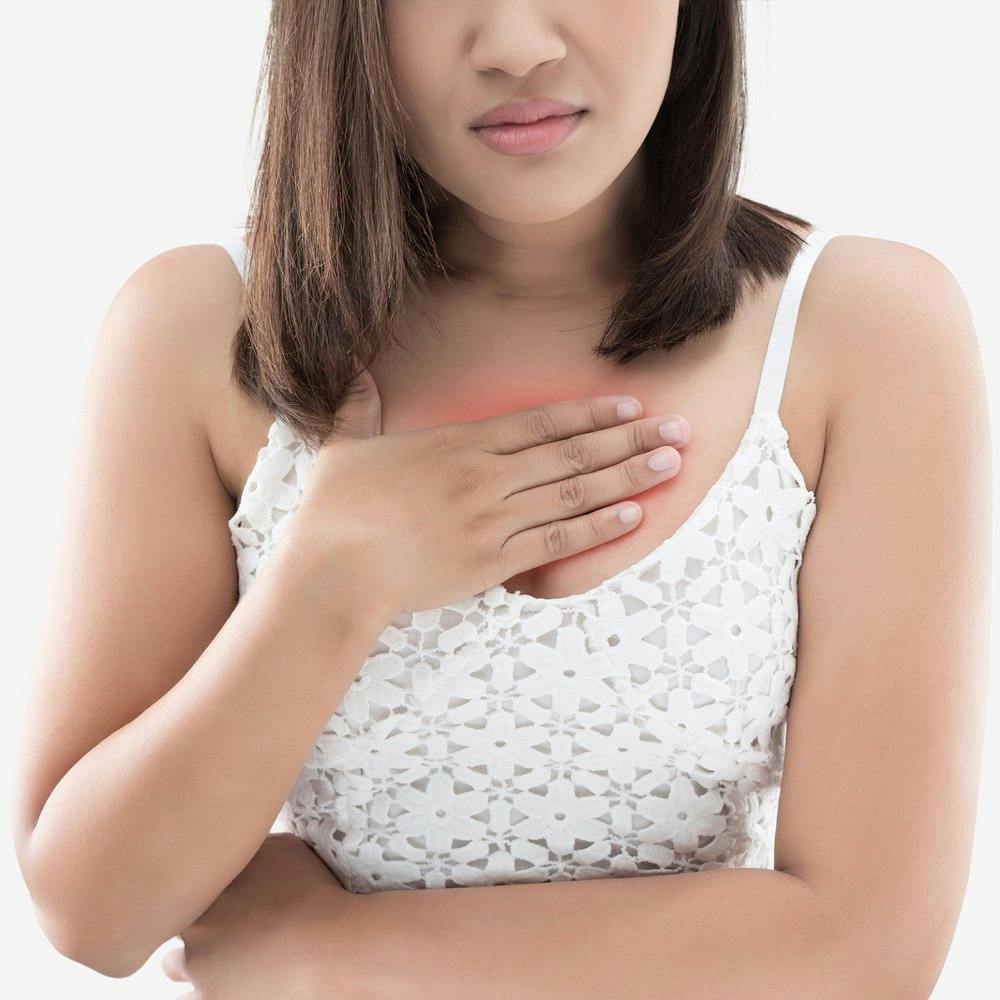 A woman suffering from heartburn holds her chest