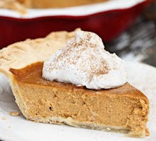 Slice of homemade pumpkin pie with whipped cream