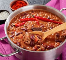 pot of chili con carne with whole red hot chilis, kidney beans and tomatoes