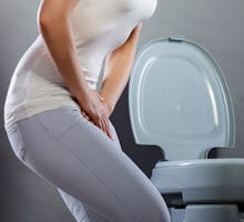 Woman suffering with interstitial cystitis near a toilet