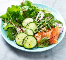 A low-carb mixed leaf salad with smoked salmon, spinach, cucumber and onions; eat to lower cholesterol