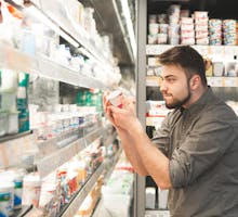 Man reading a yogurt label at the supermarket