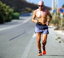 bald man jogging in running shorts in the sun