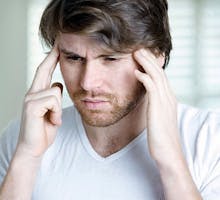 man with a headache holding his temples in pain