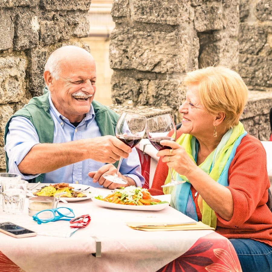 Senior couple having fun and eating at restaurant during travel &#8211; Mature man and woman wife in old city town bar during active elderly vacation &#8211; Happy retirement concept with retired people together
