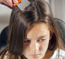 Mother fighting lice by treating daughter's hair with nit comb