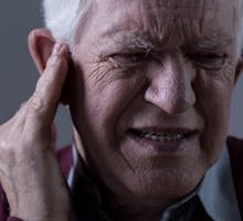 Old man suffering from tinnitus or ringing in the ear