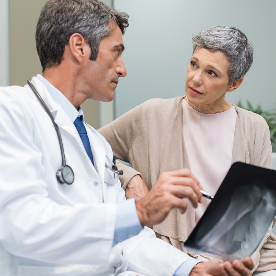 Male doctor and senior patient discussing scan results at the office. Doctor showing to senior woman x-ray in a medical clinic. Mature doctor showing a radiography to his patient.

