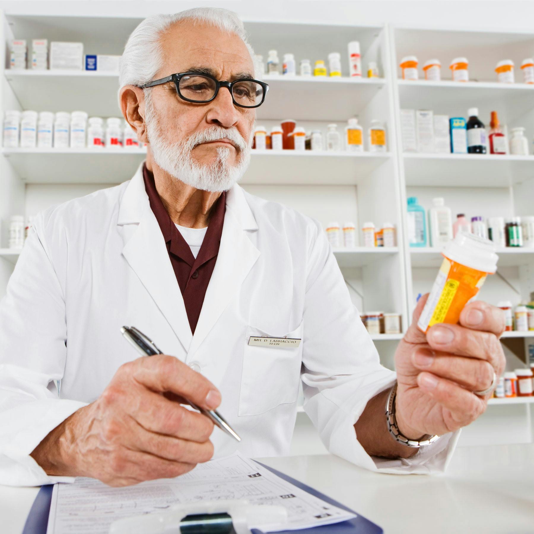An older local pharmacist reads a pill bottle