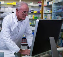 Older male pharmacist working on computer