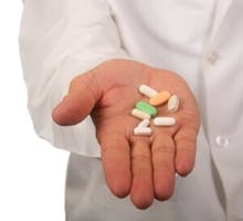 doctor in a lab coat with a handful of pills