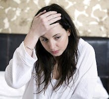 woman sick with a cold or the flu holds her head