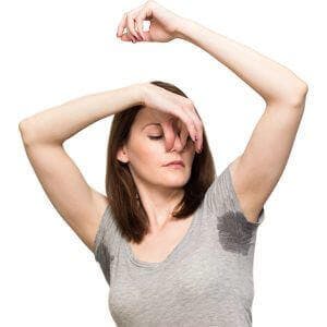 a woman with sweaty and smelly underarms holding her nose