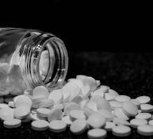 A aspirin bottle open and aspirin pills spilled out
