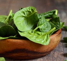 Spinach leaves in a rustic wooden bowl.