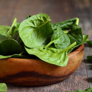 Spinach leaves in a rustic wooden bowl.