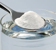 a spoon poised to dissolve baking soda in water