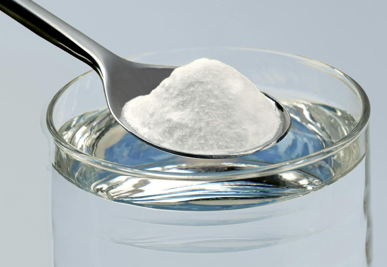 a spoon poised to dissolve baking soda in water