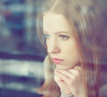 A young women suffering from seasonal affective disorder (SAD) looks out the window