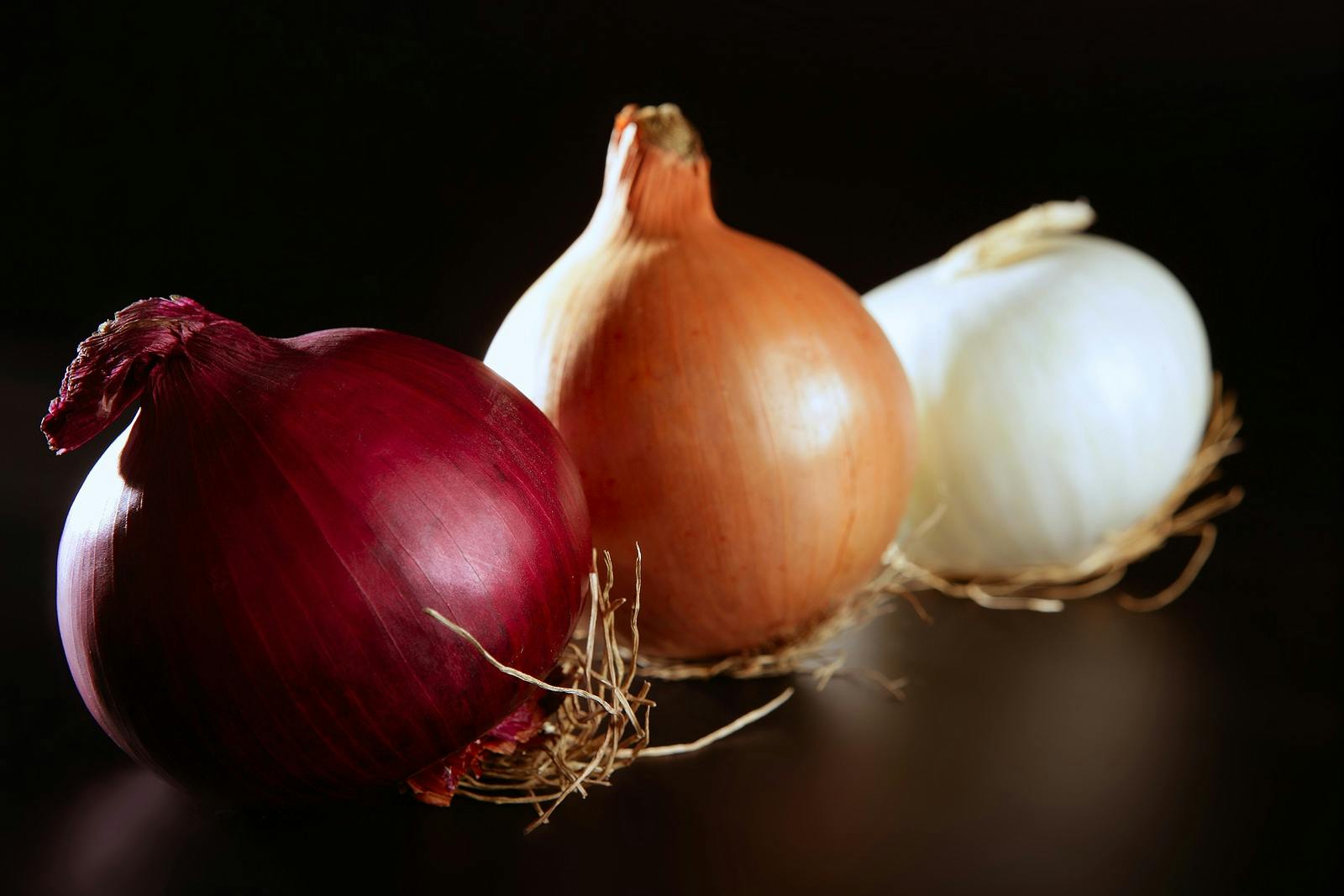 Three colorful different onion in varied colors over black
