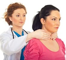 female doctor performing thyroid exam on a female patient