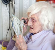 older woman with age-related macular degeneration using magnifying glass