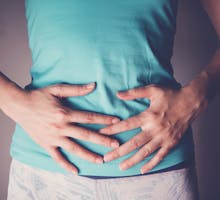 woman has hands on her abdomen for symptoms of IBS