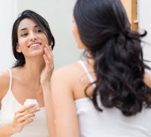 Young woman applying moisturizer to her face