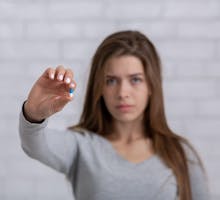 Young woman holding a fluvoxamine antidepressant pill