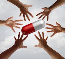 Hands reaching for giant pill for coronavirus drug shortages