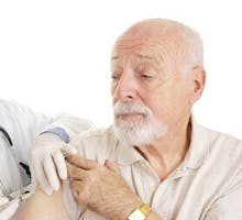 older man with a beard getting a shot in his arm