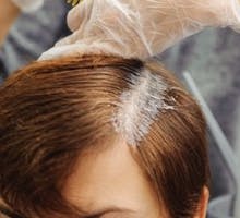 gray roots being dyed with hair dye at a salon