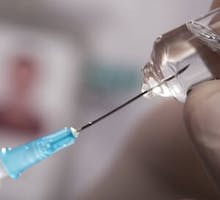a hypodermic needle inserted into a vial of medicine